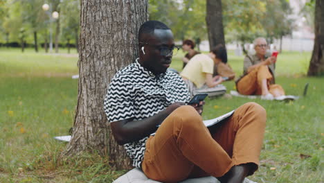 Joven-Negro-Usando-Un-Teléfono-Inteligente-En-El-Parque